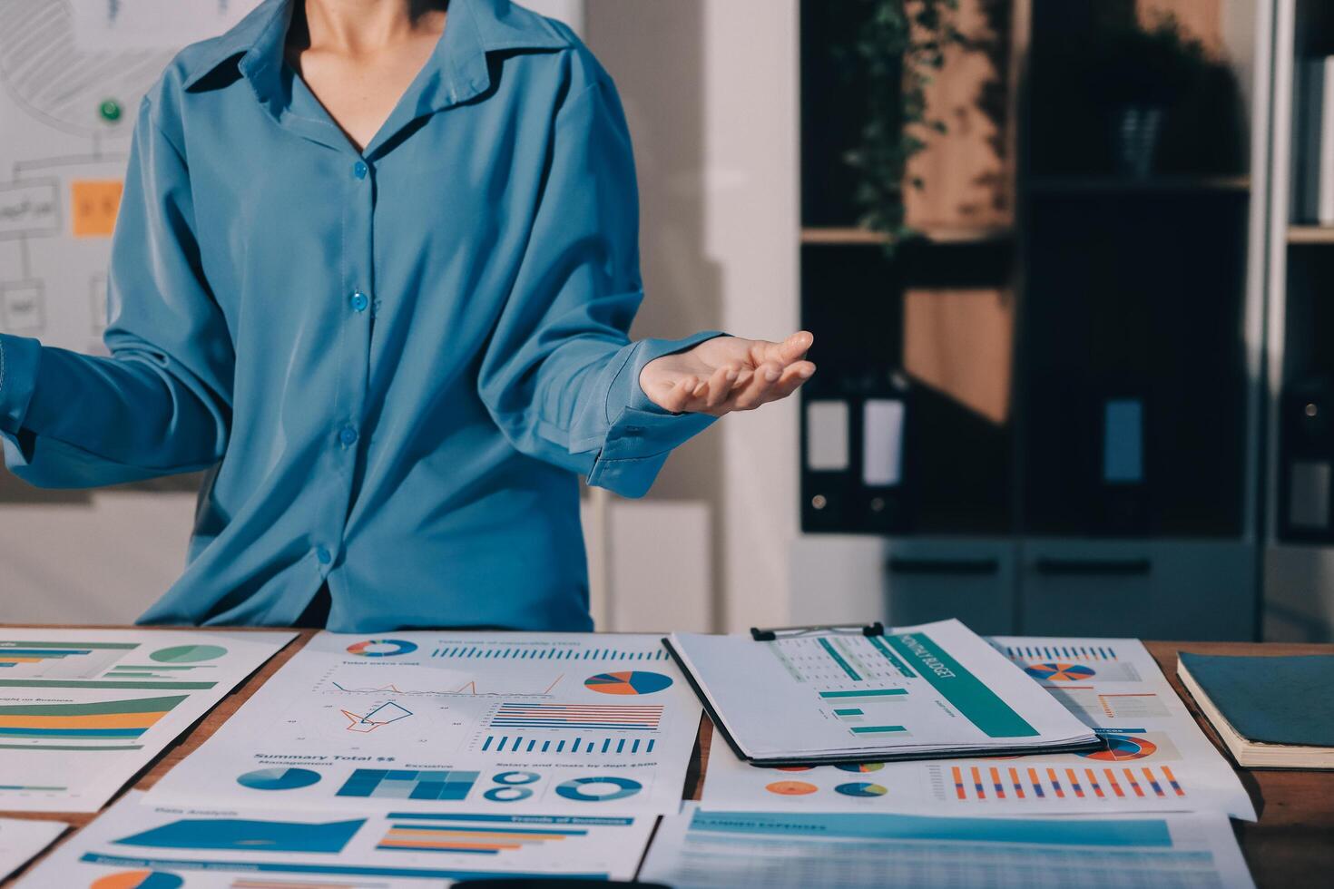 A woman standing in front of a table with graphs and papers photo