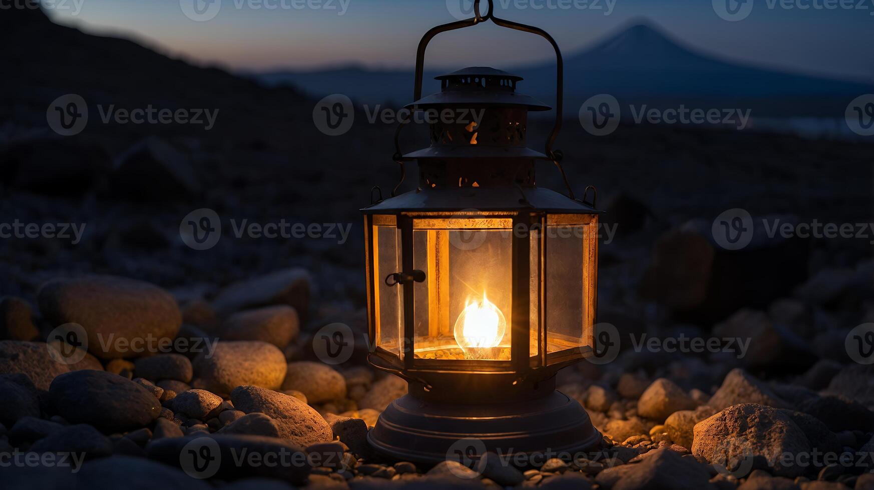 Illuminated Lantern on Rocky Ground at Dusk photo
