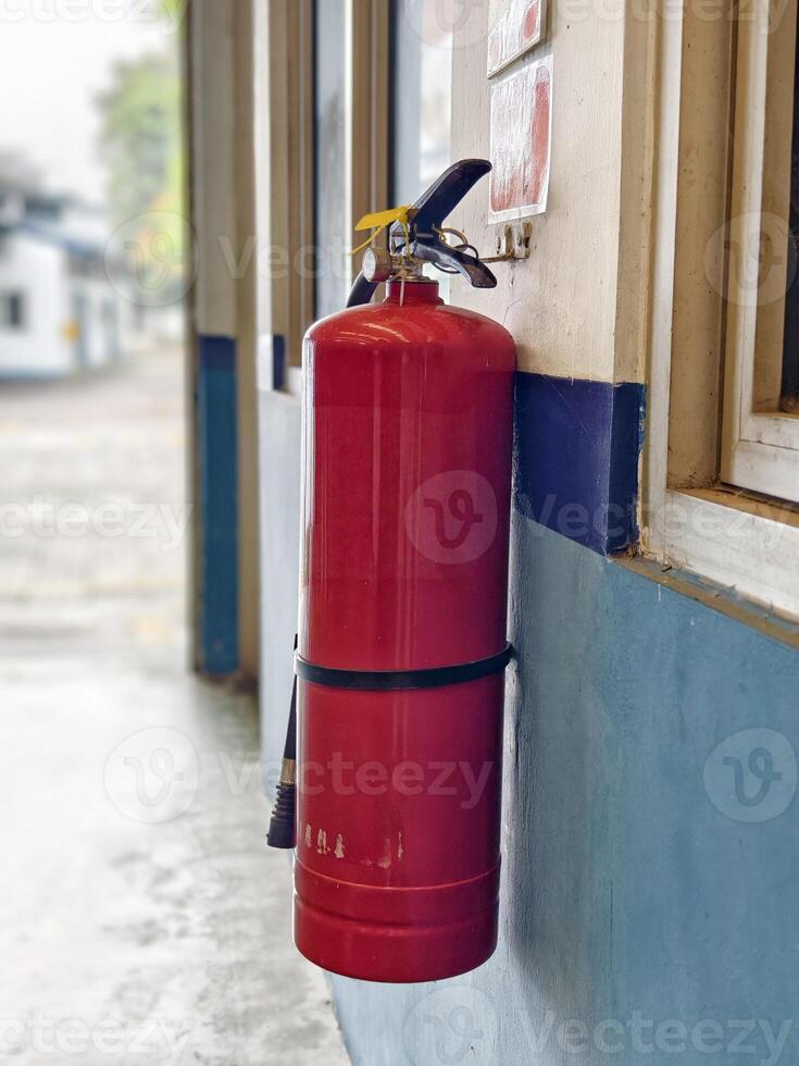 Red Fire Extinguisher Mounted on Blue Wall in Industrial Corridor, photo