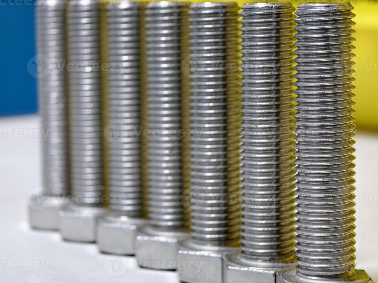 Detailed close-up of shiny metal bolts aligned in rows on a white surface, showcasing industrial precision and durability photo