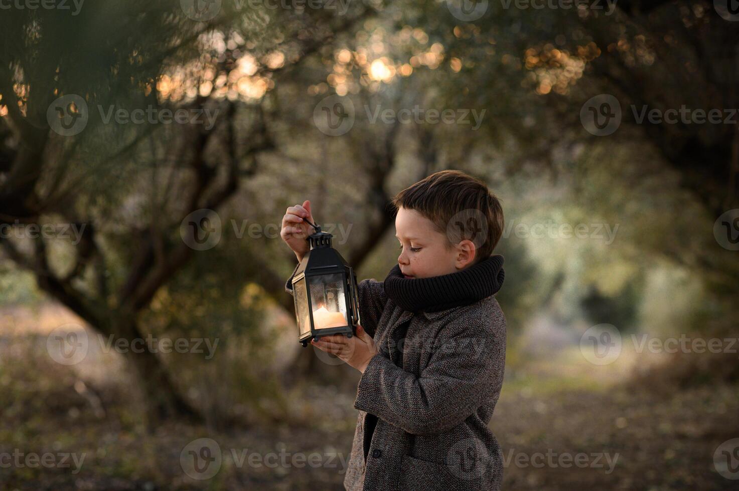 A child explores a mysterious woodland, staring at the flickering lantern in his hands, surrounded by magical light. photo