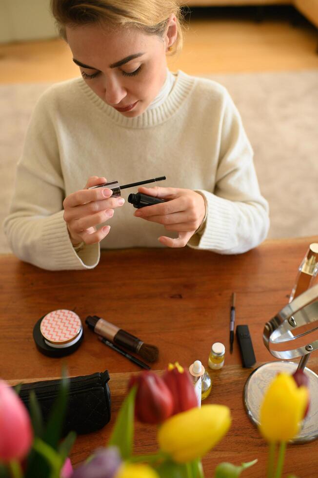 Close-up of a young woman putting on mascara, concentrating on creating a bold lash look. photo