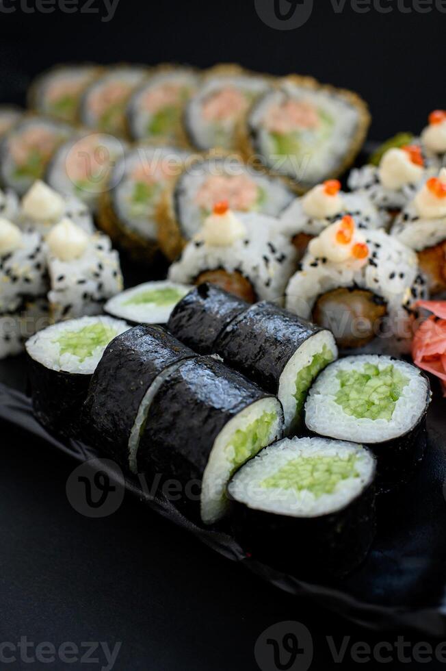 Gourmet sushi platter and maki rolls served on black slate, highlighting texture and freshness. photo