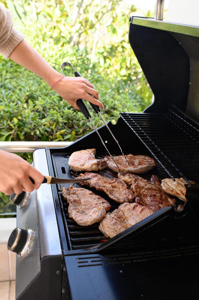 A hand carefully slices grilled chicken while flipping sizzling meat on the barbecue. photo