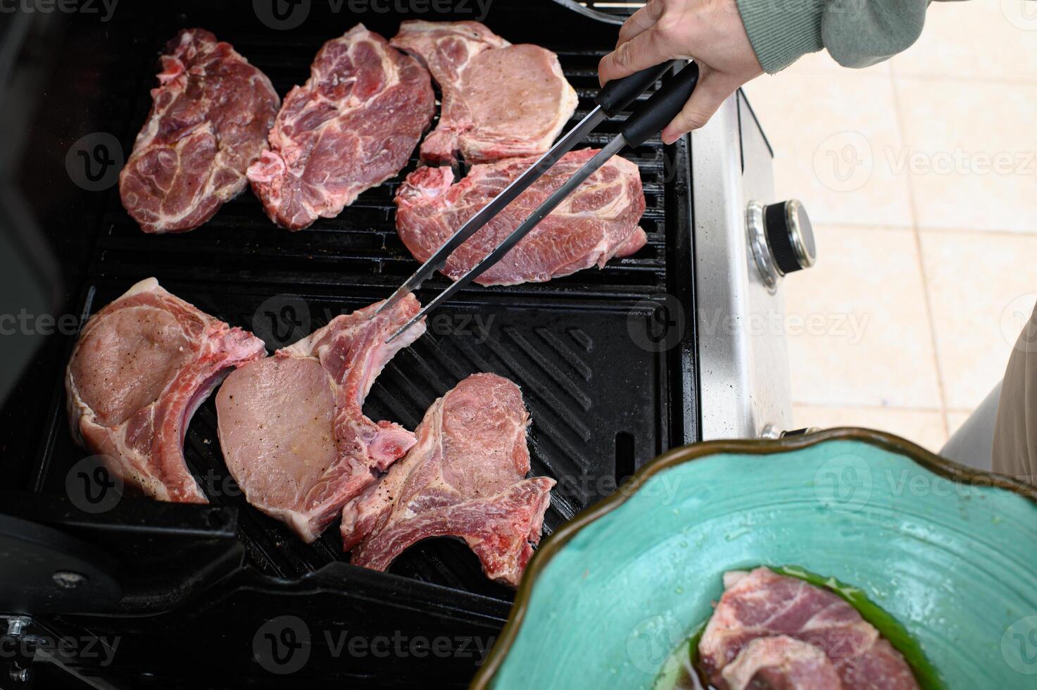 Hands arrange uncooked steaks on the smoking grill, with marinated mushrooms set aside, waiting their turn. photo