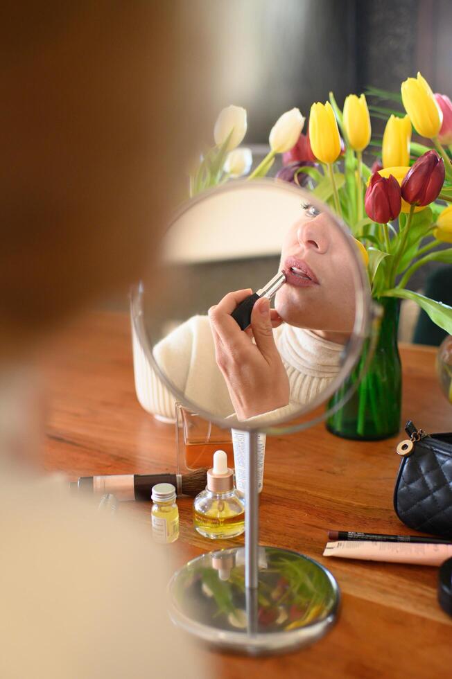 A detailed view of lips being colored with lipstick, reflected in a small vanity mirror. photo