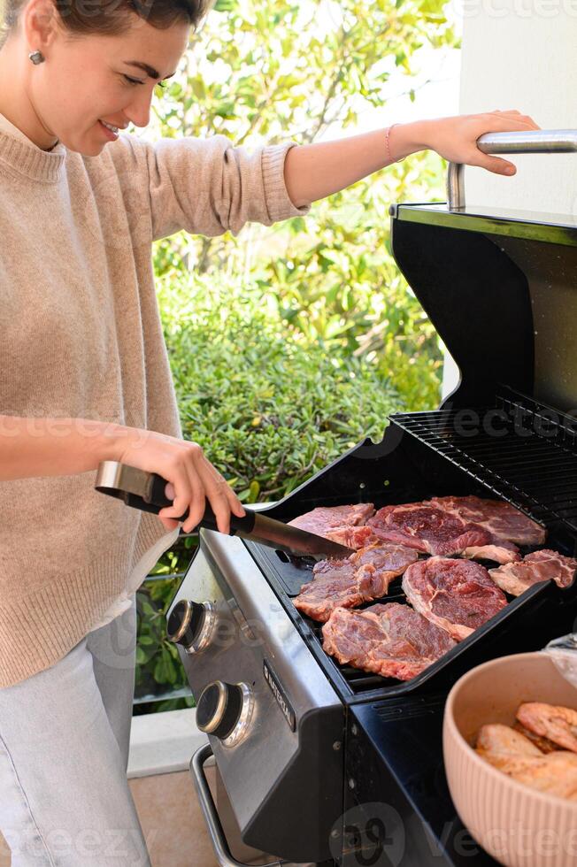 Over the hot coals, raw meat sears while a colorful dish of chicken waits on the side. photo