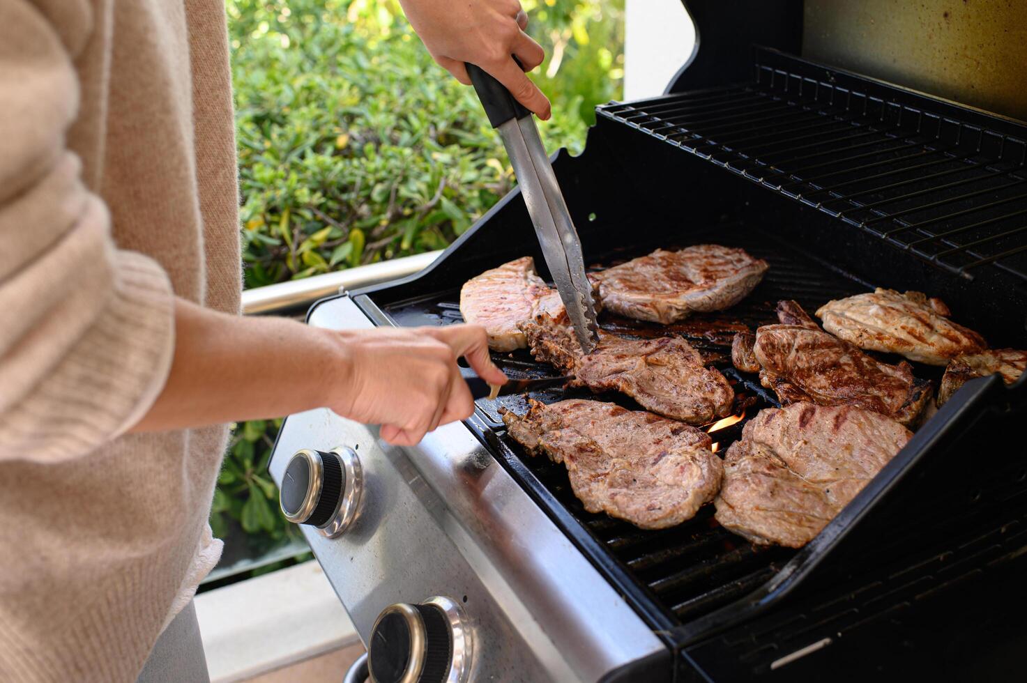 Grilled chicken and beef are turned with tongs over the hot flames, browning perfectly. photo