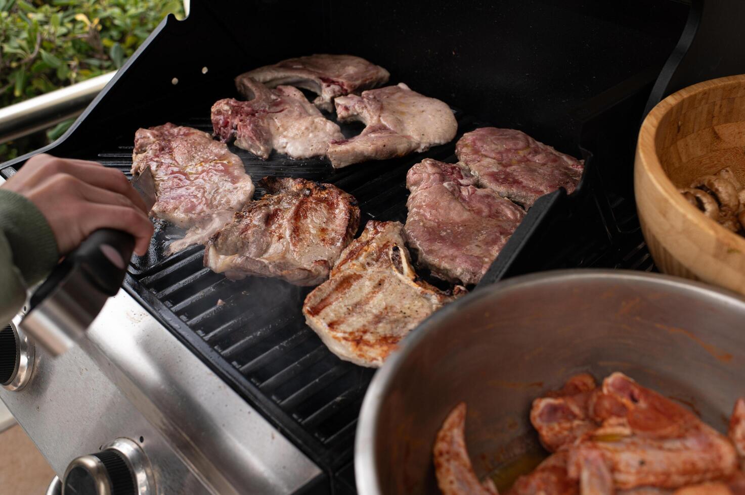 Golden-brown pork and seared beef crackle on the grill, smoke curling upward, as raw chicken sits on a dish to the side, ready for the flames. photo