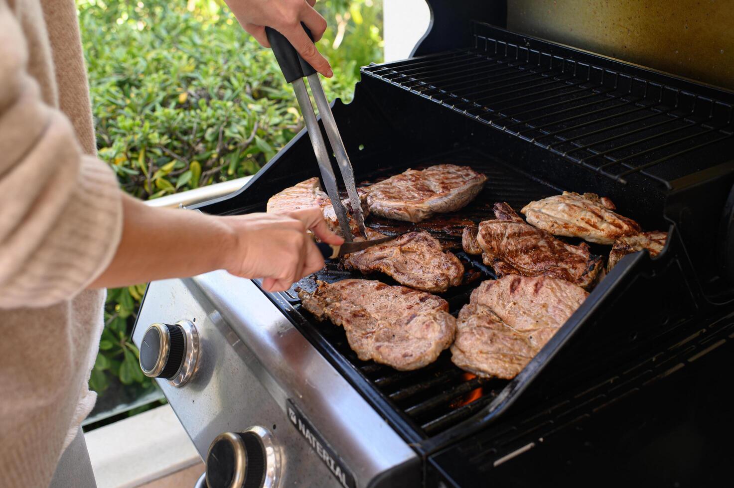 Steak and chicken are being grilled to perfection, flipped with tongs and carved for serving. photo