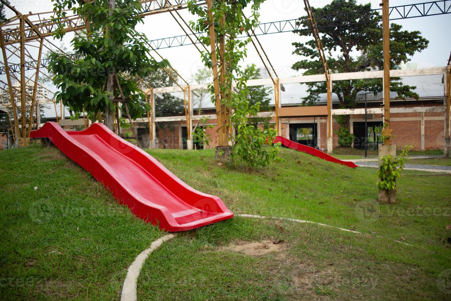 Red slide on grassy slope in unfinished building structure photo