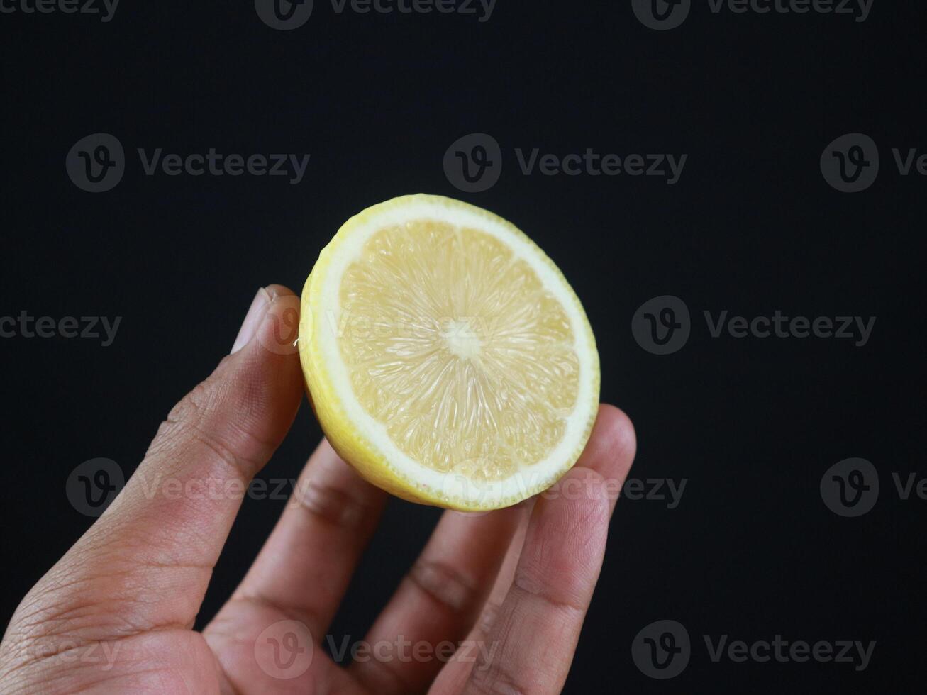 A man holds halves of a cut lemon in his hands. Exotic fruits in hands. Lemon close up, black background photo