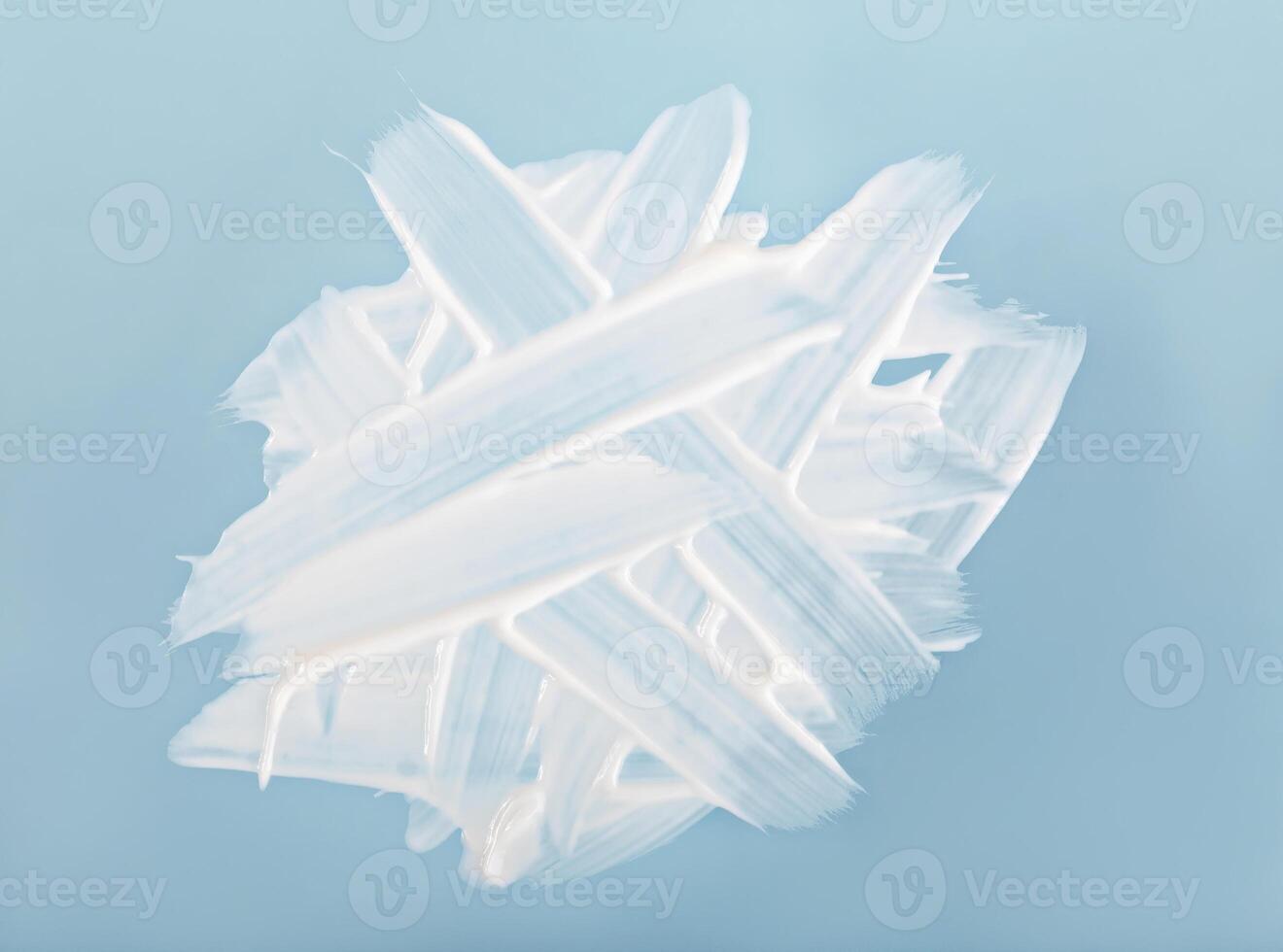White cream strokes layered on blue background, abstract texture of cream strokes, concept of skincare cream, product design, soft composition for beauty and wellness. Cream strokes create texture photo