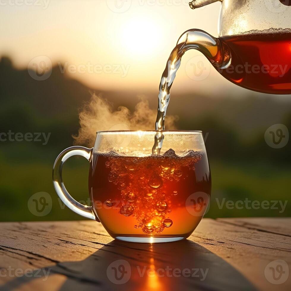 Pouring Hot Tea Into A Glass Cup At Sunset Outdoors Background With Steam photo