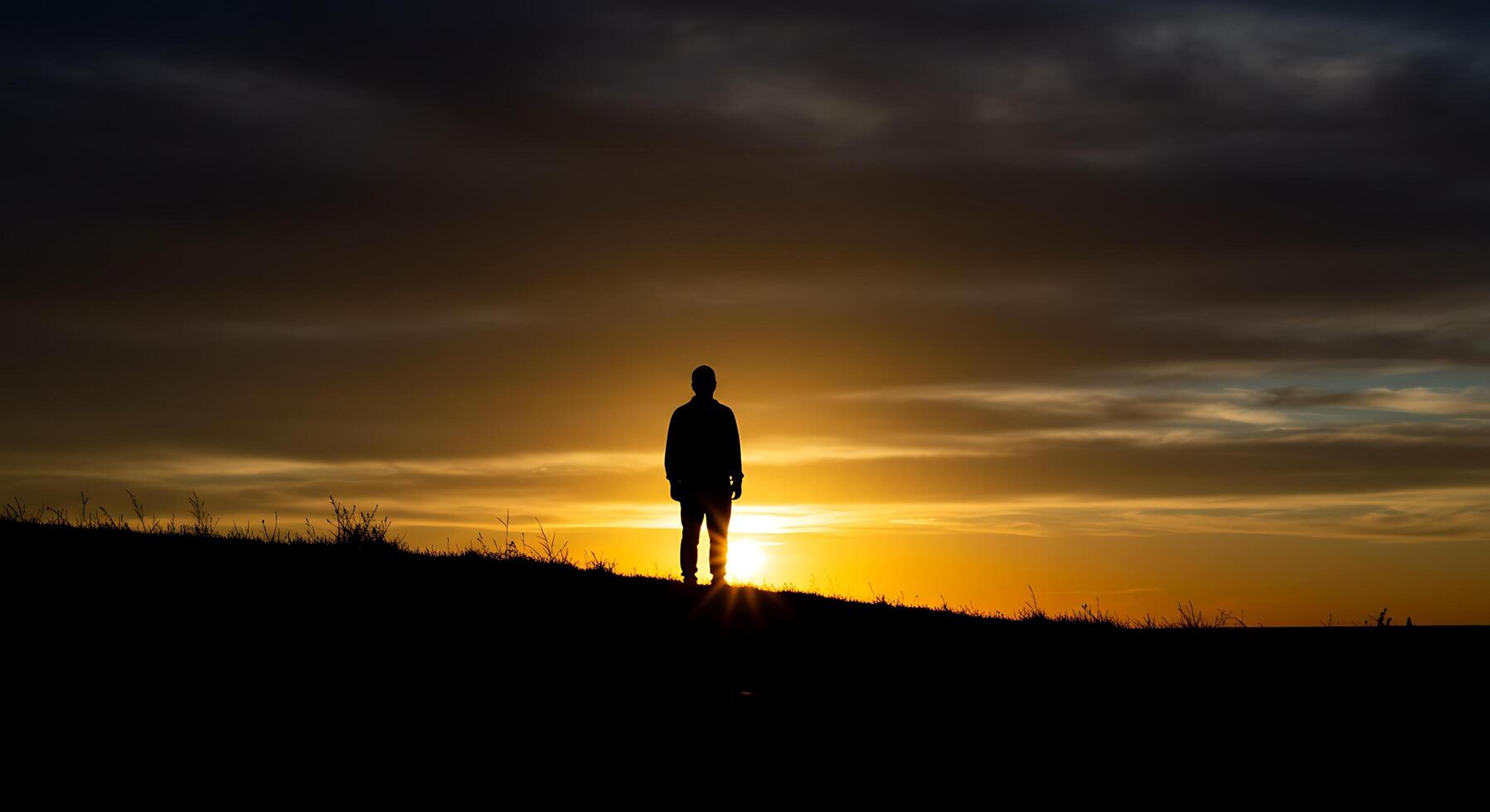 Silhouette of a man watching the sunset on a hill photo