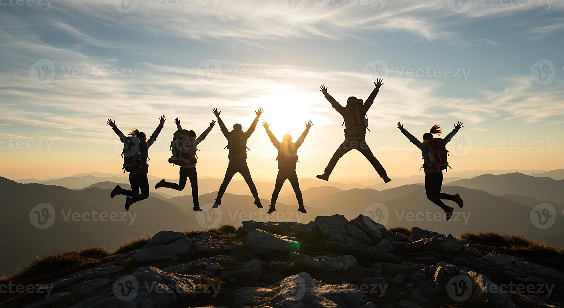 Silhouette of Joyful Hikers Jumping on Mountain Peak at Sunset photo