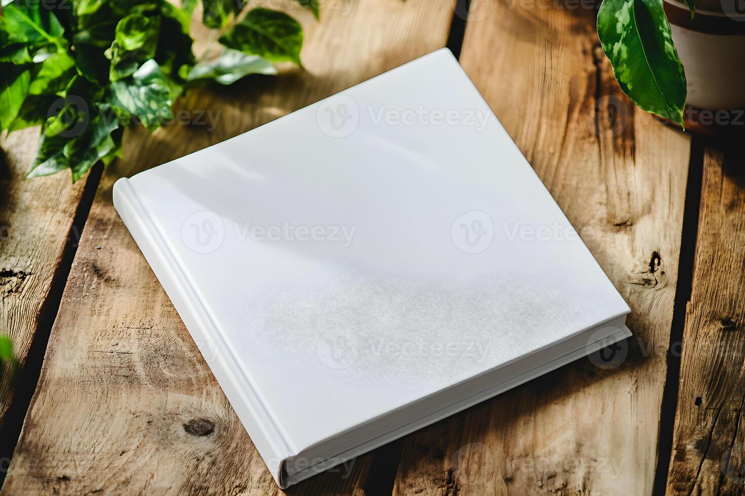 Blank notebook for mockup resting on a rustic wooden table surrounded by vibrant green plants creating a serene workspace atmosphere photo