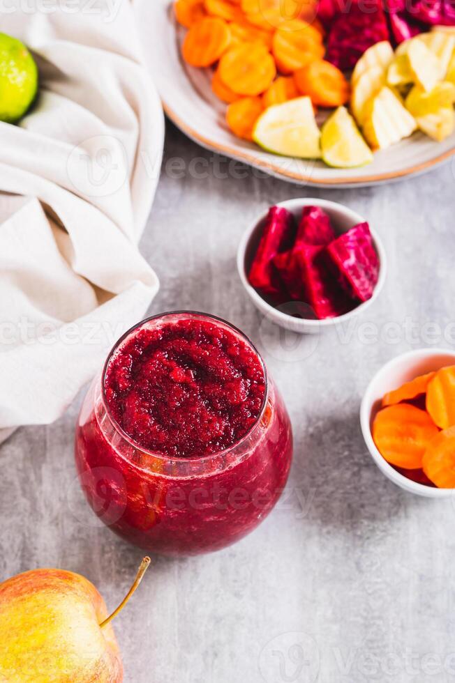 A glass with a mixture of beetroot, apple and carrot juices ABC on the table vertical view photo