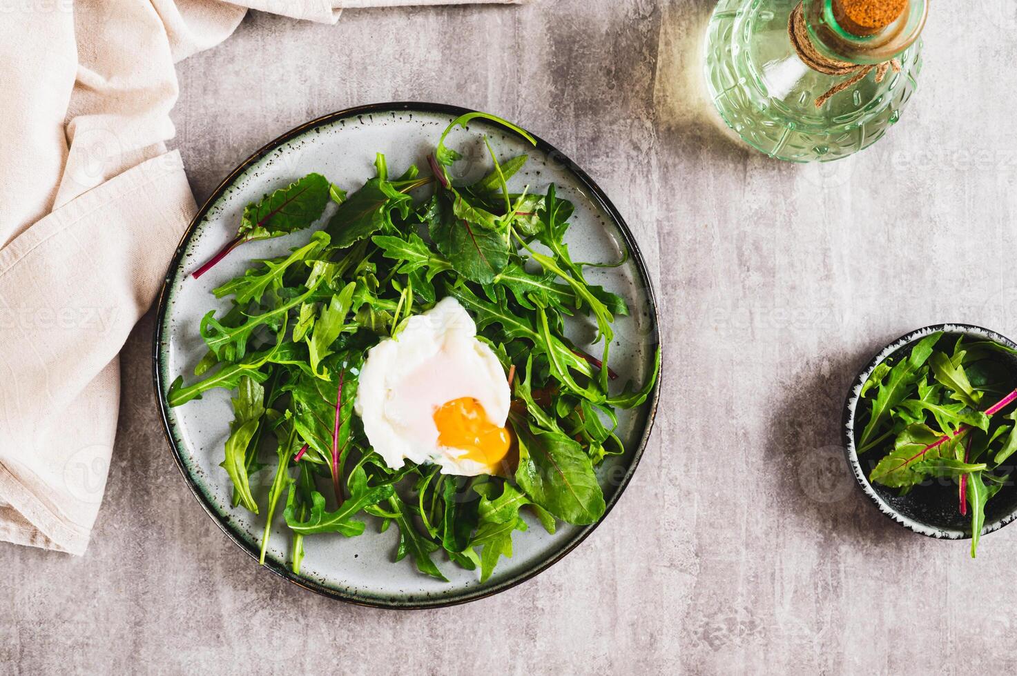 Poached egg in arugula and chard leaves on a plate on a table top view photo