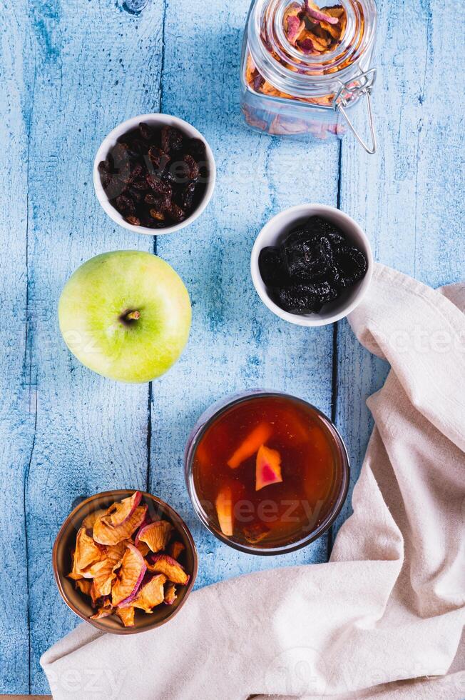 Sweet dried fruit compote in a glass on the table top and vertical view photo