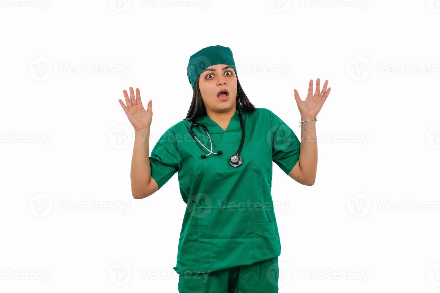 Latin female surgeon wearing green scrubs showing surprise with raised hands photo