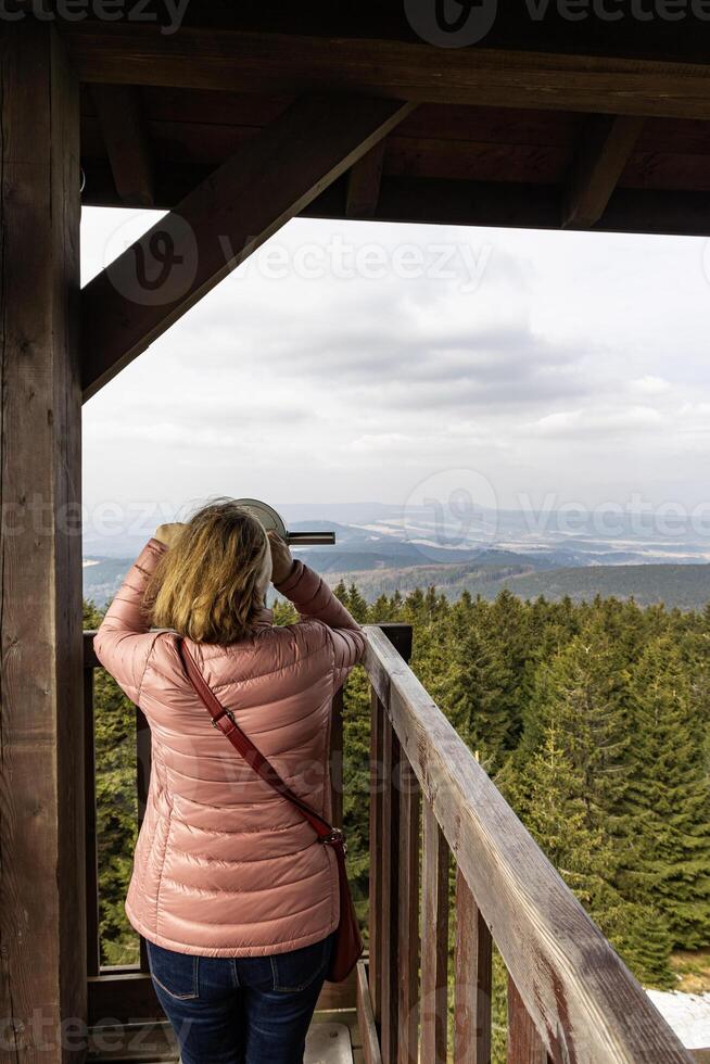 Woman looking through a telescope at a mountain landscape. Eastern Sudetes on the border of Poland and the Czech Republic photo