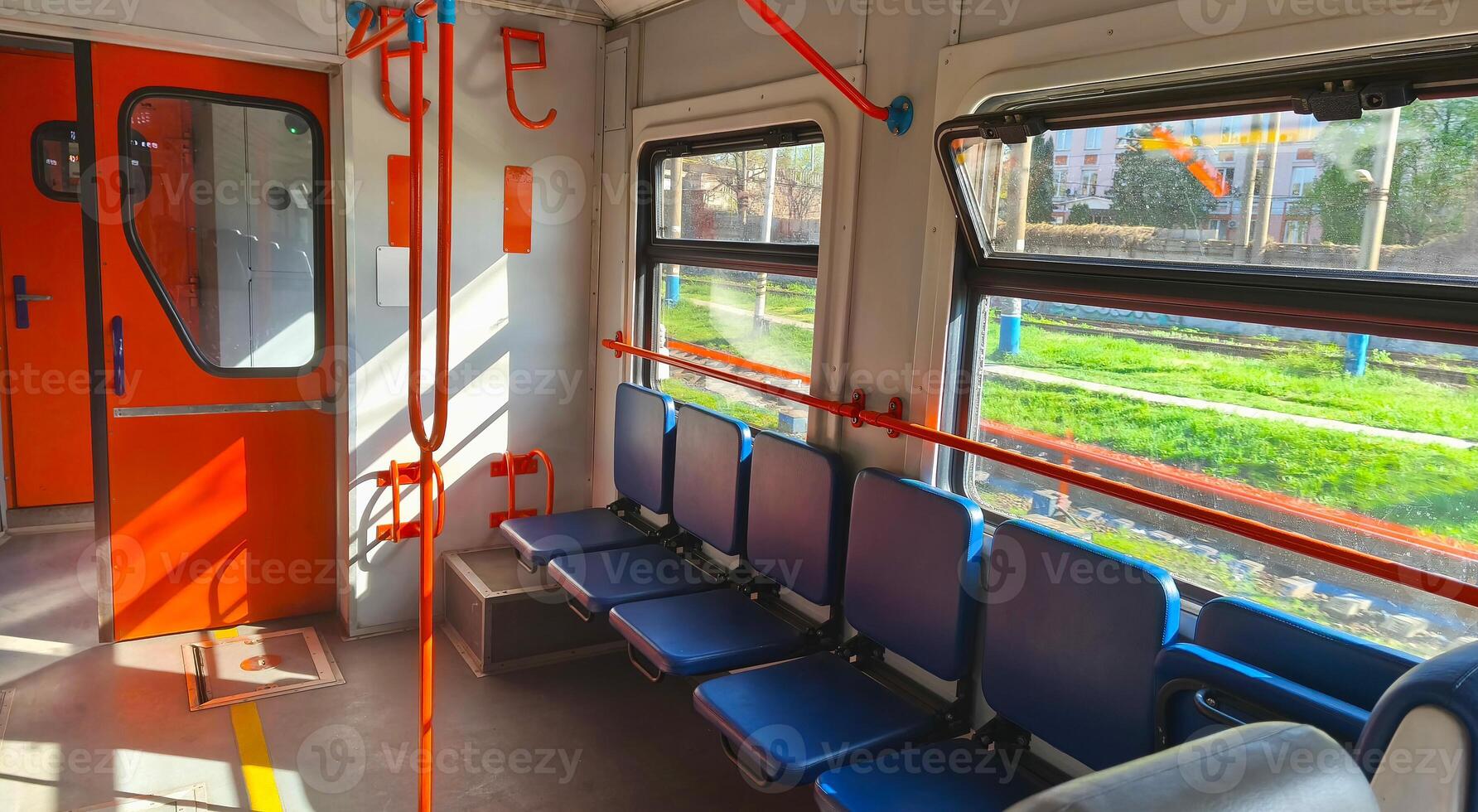 Interior of an empty city train carriage with blue seats and orange handrails. Passenger train. Empty seats in the carriage. Intercity. photo