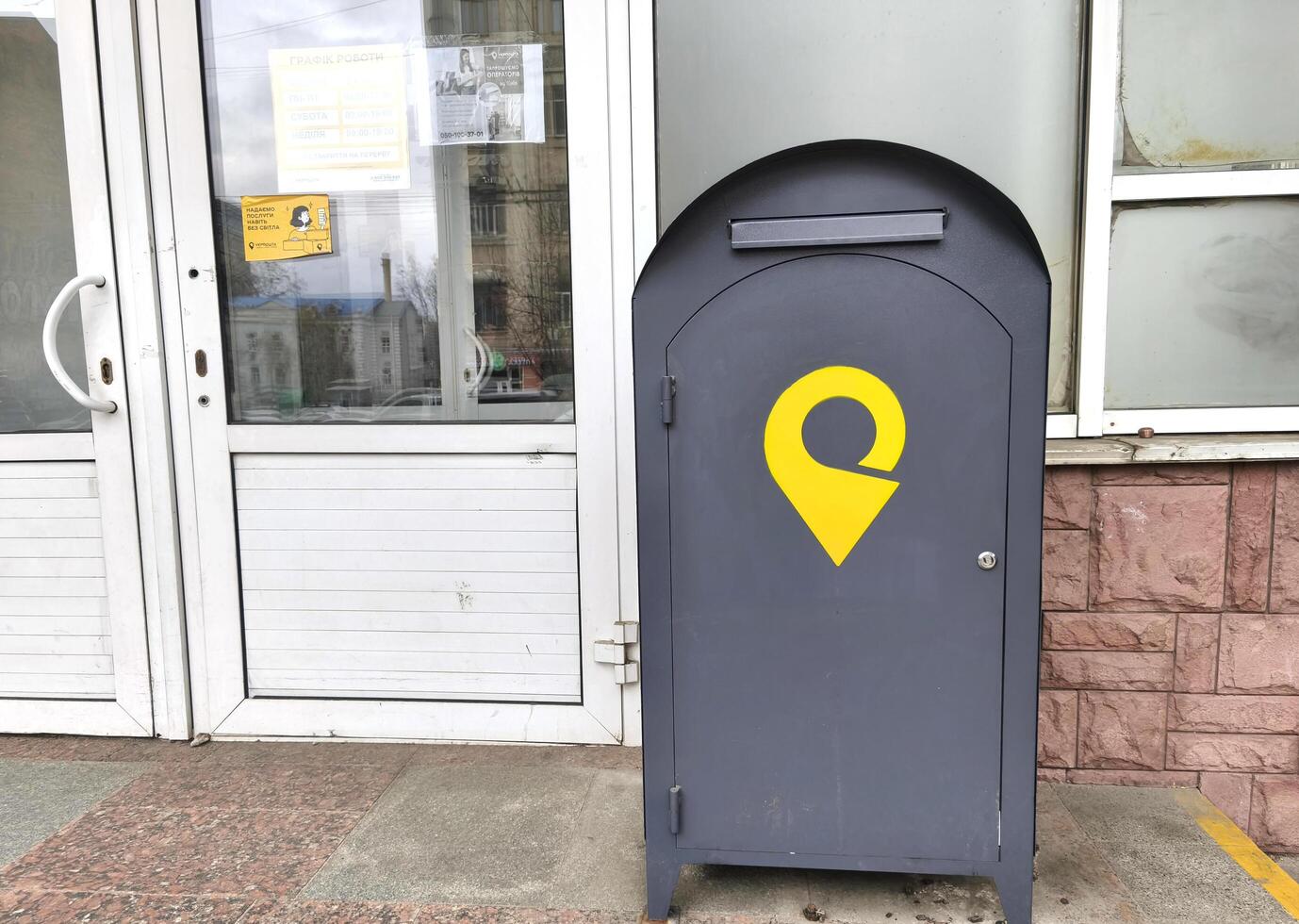 Kyiv, Ukraine - April 7, 2025 A gray metal letter box with a yellow Ukrposhta logo near the city post office photo