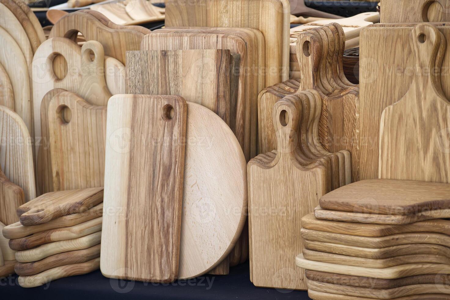 Handcrafted wooden cutting boards in various shapes and sizes are displayed at local artisan market photo