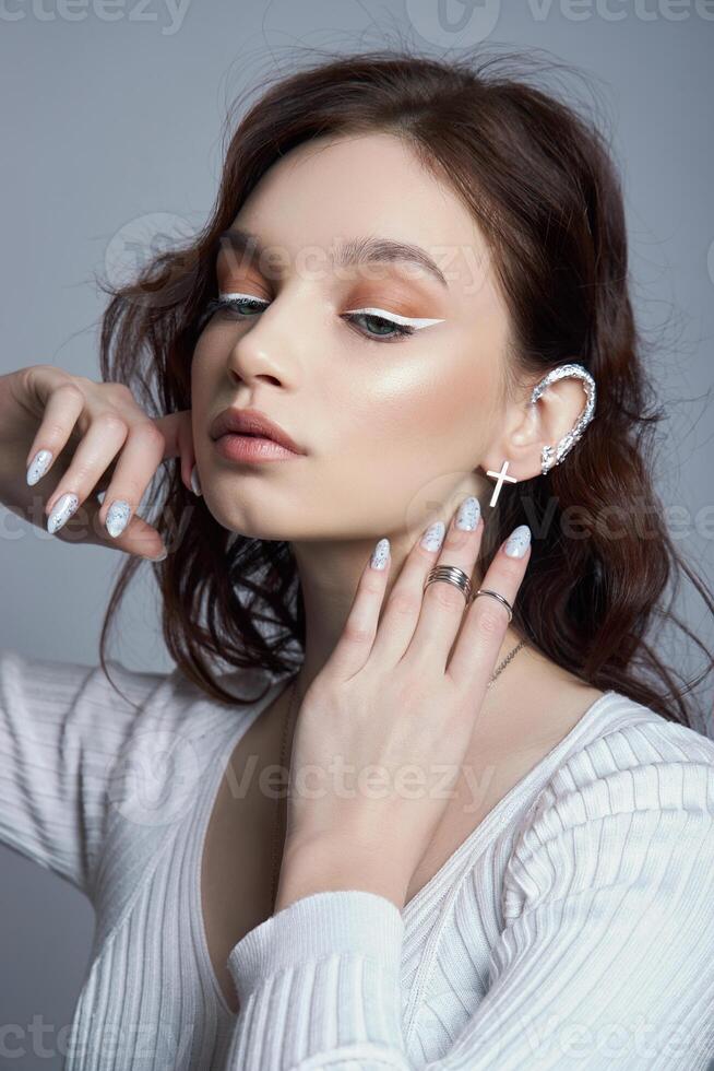 Beauty portrait of woman with natural makeup and painted polished nails on her hand. Rings on the fingers of the hand photo