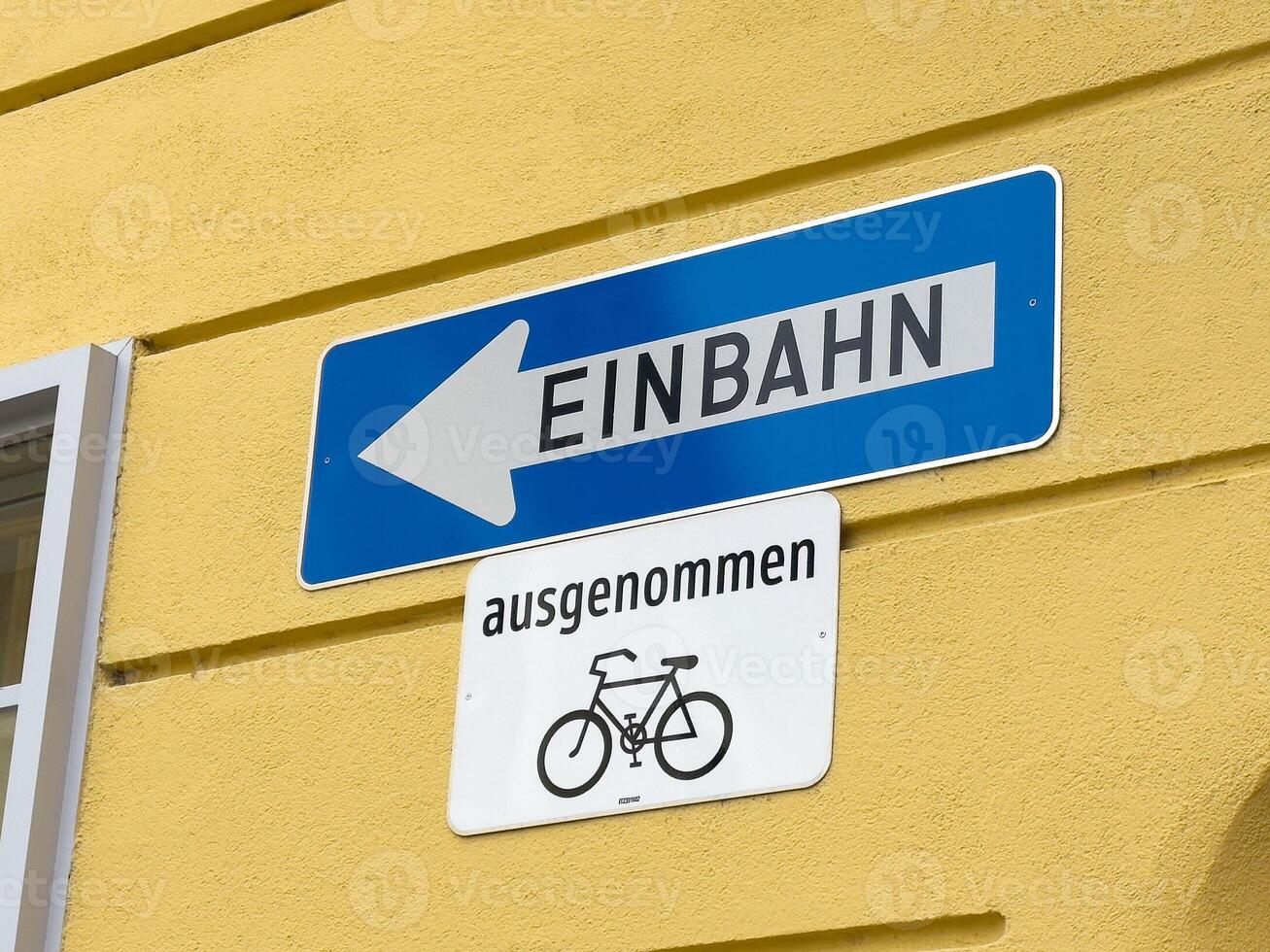 German one way street sign with bicycle exception on yellow wall photo