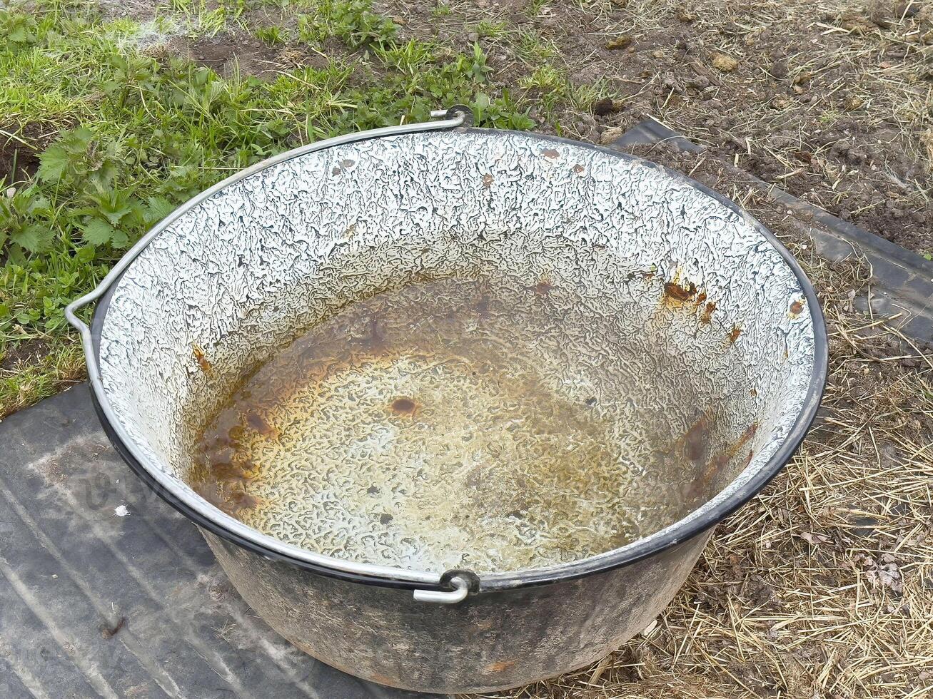 Rusty metal basin on outdoor ground surface weathered container in natural setting photo