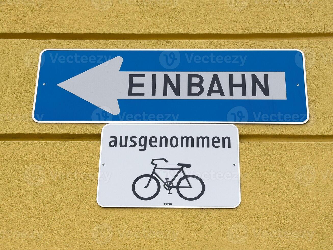 German one way city street sign with bicycle exception on yellow wall photo
