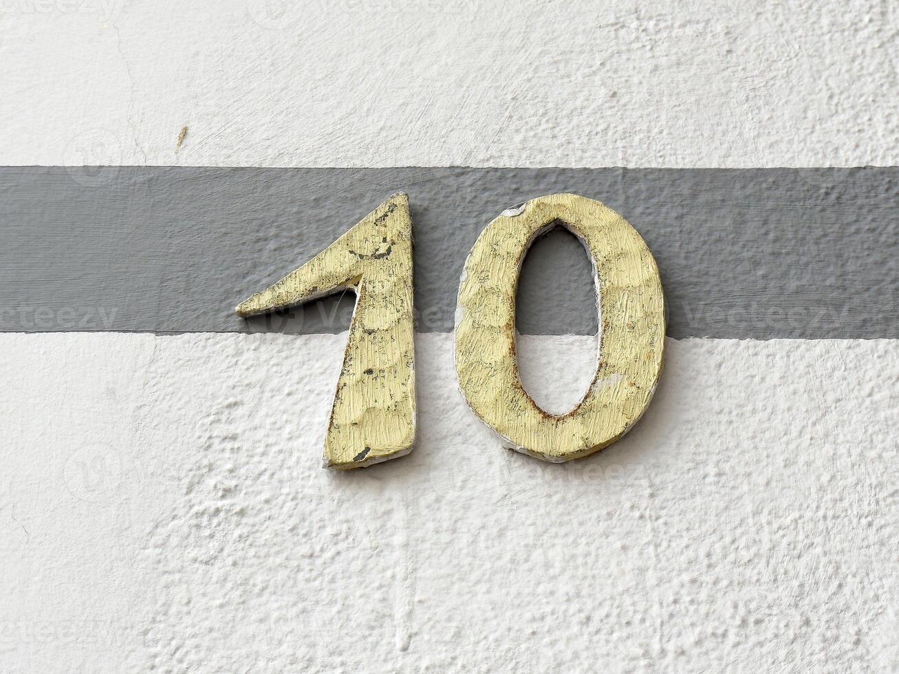 Weathered number ten on textured gray and white wall photo