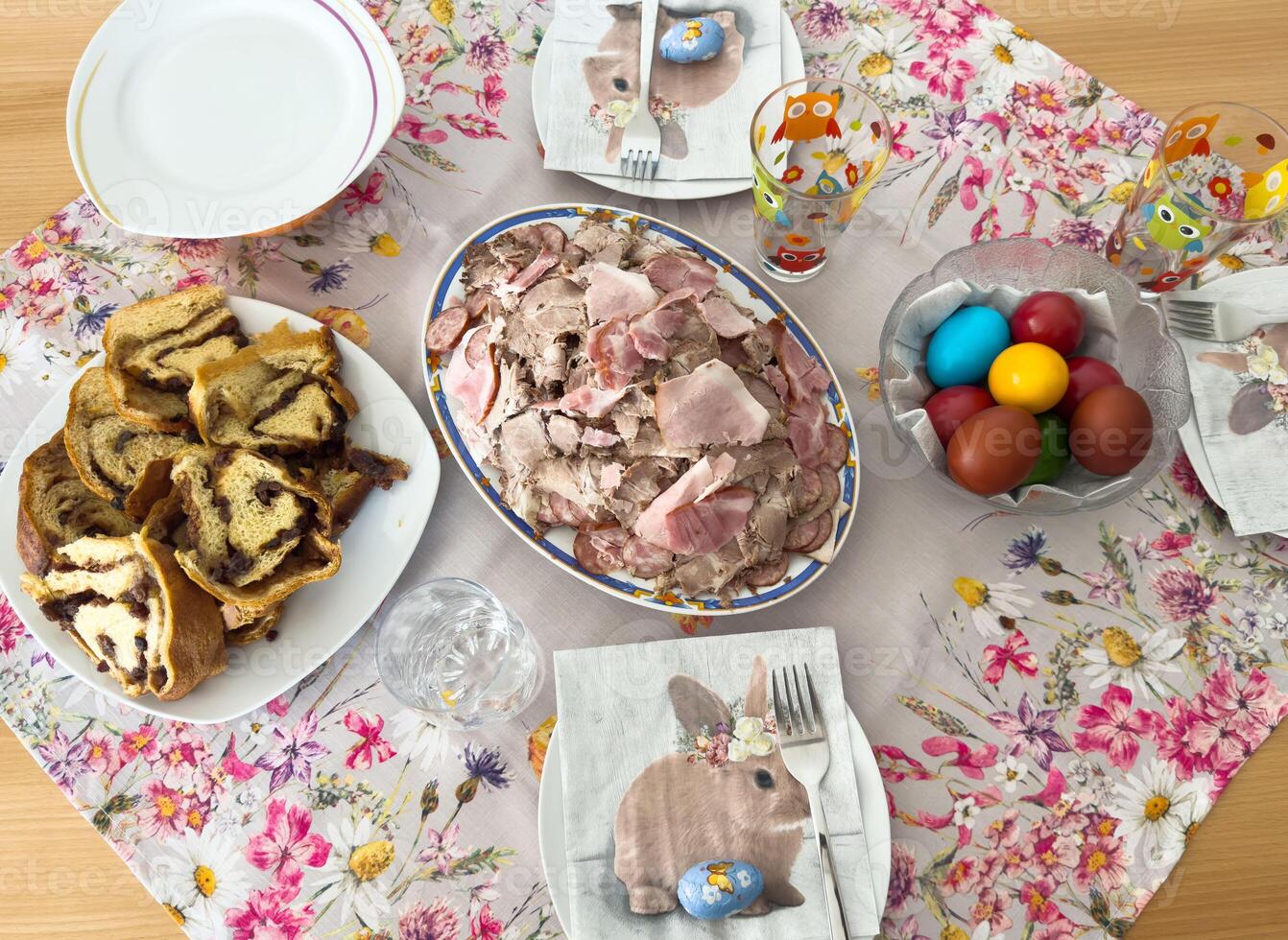 Easter table with cold cuts, easter eggs, and marble cake on floral tablecloth photo
