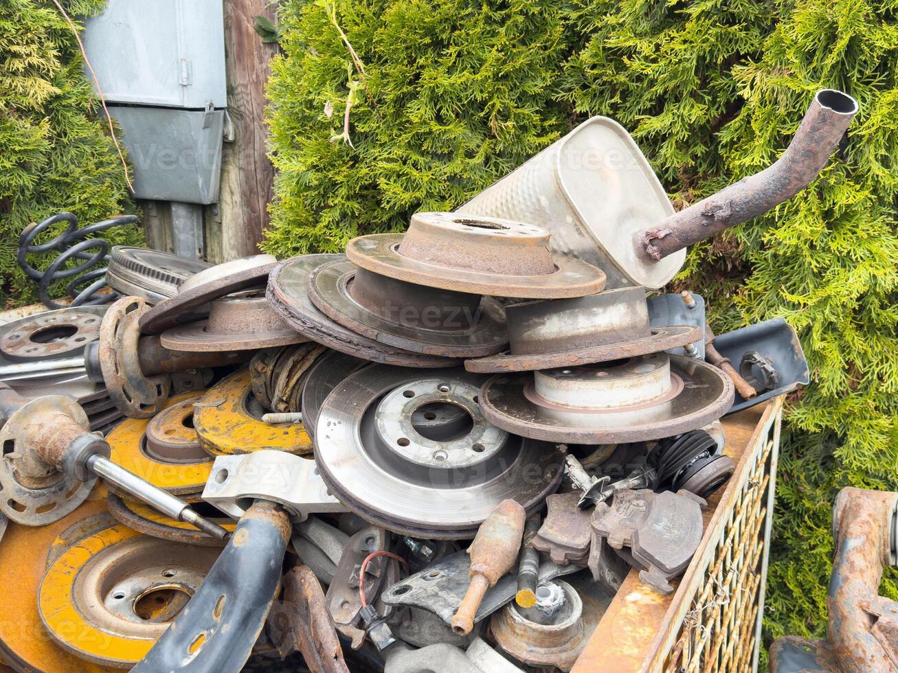 Rusty car parts pile with brake discs and exhaust in outdoor junkyard setting photo