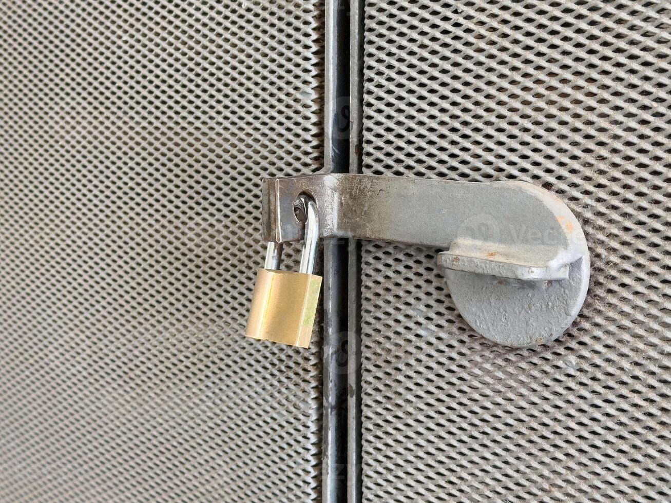 Metal gate with padlock on rusty mesh fence for security and protection photo