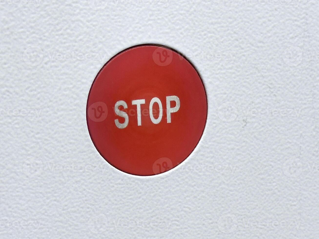 Red stop button on white textured surface for emergency use photo