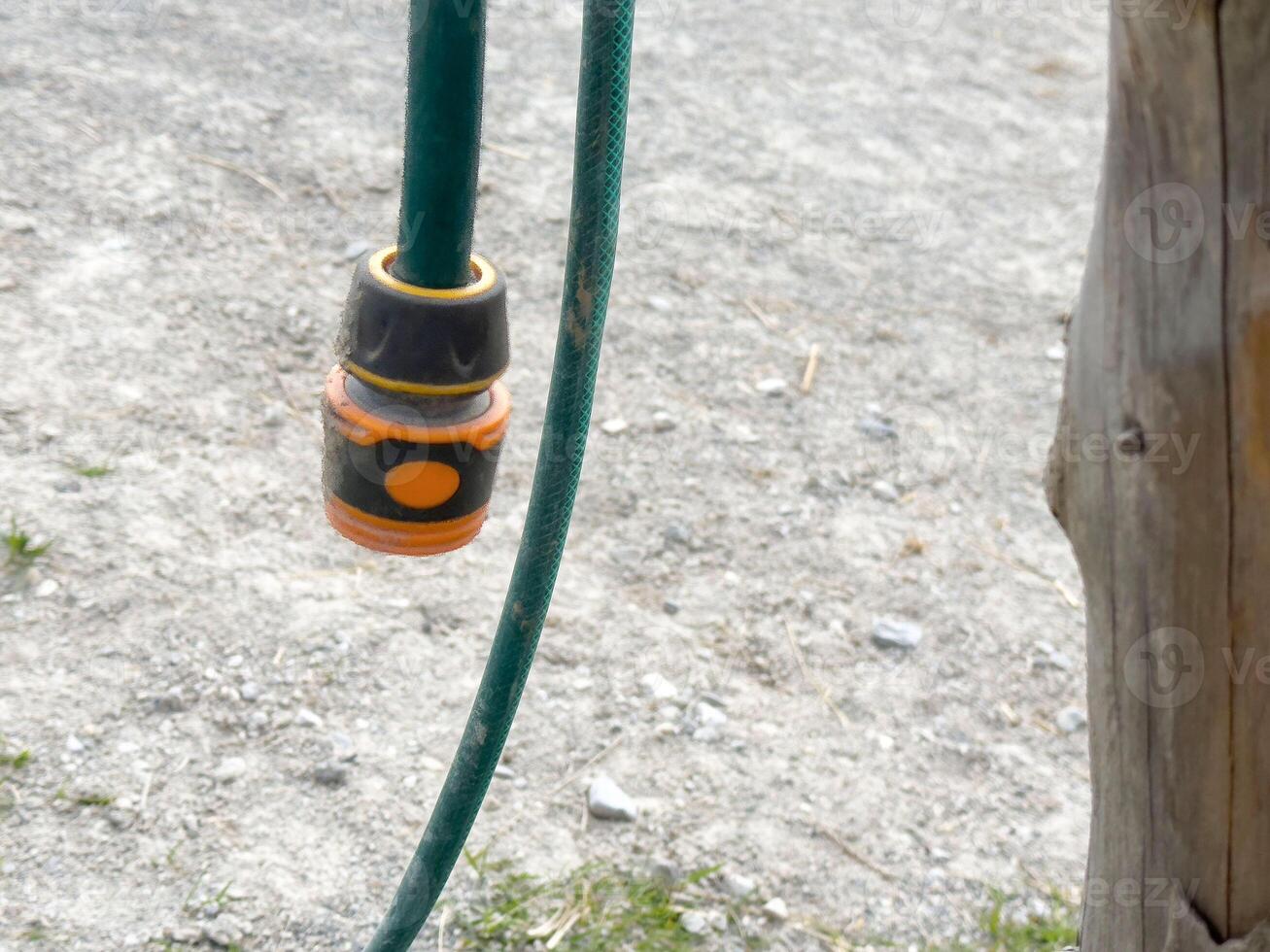 Outdoor water hose with connector on gravel surface photo