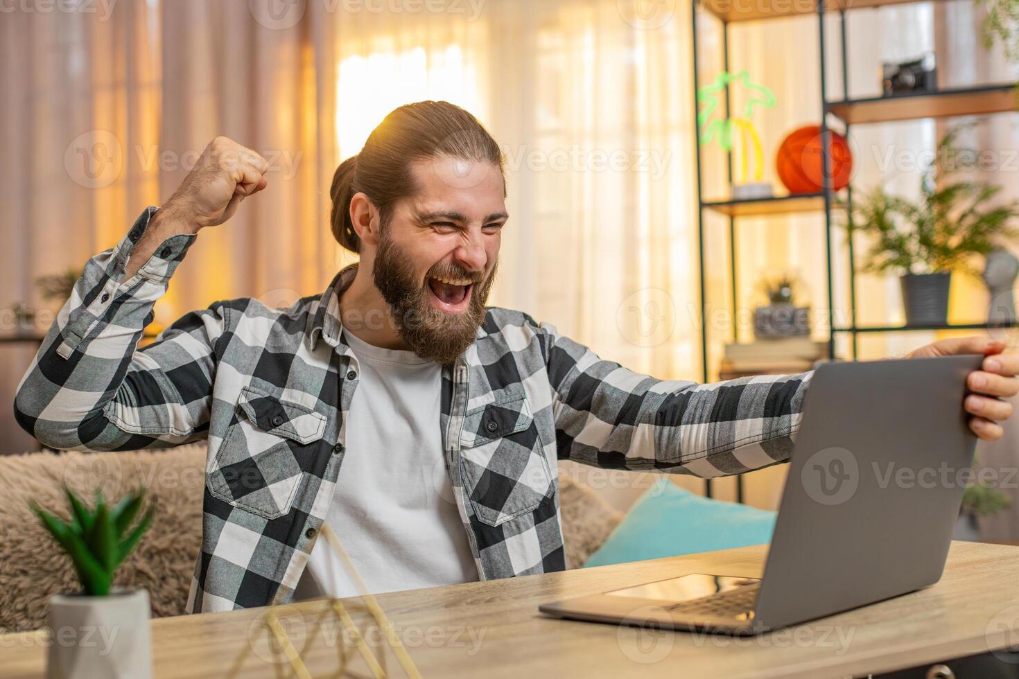 Young man man opens laptop at home wow great winning result in an online course celebrates victory photo