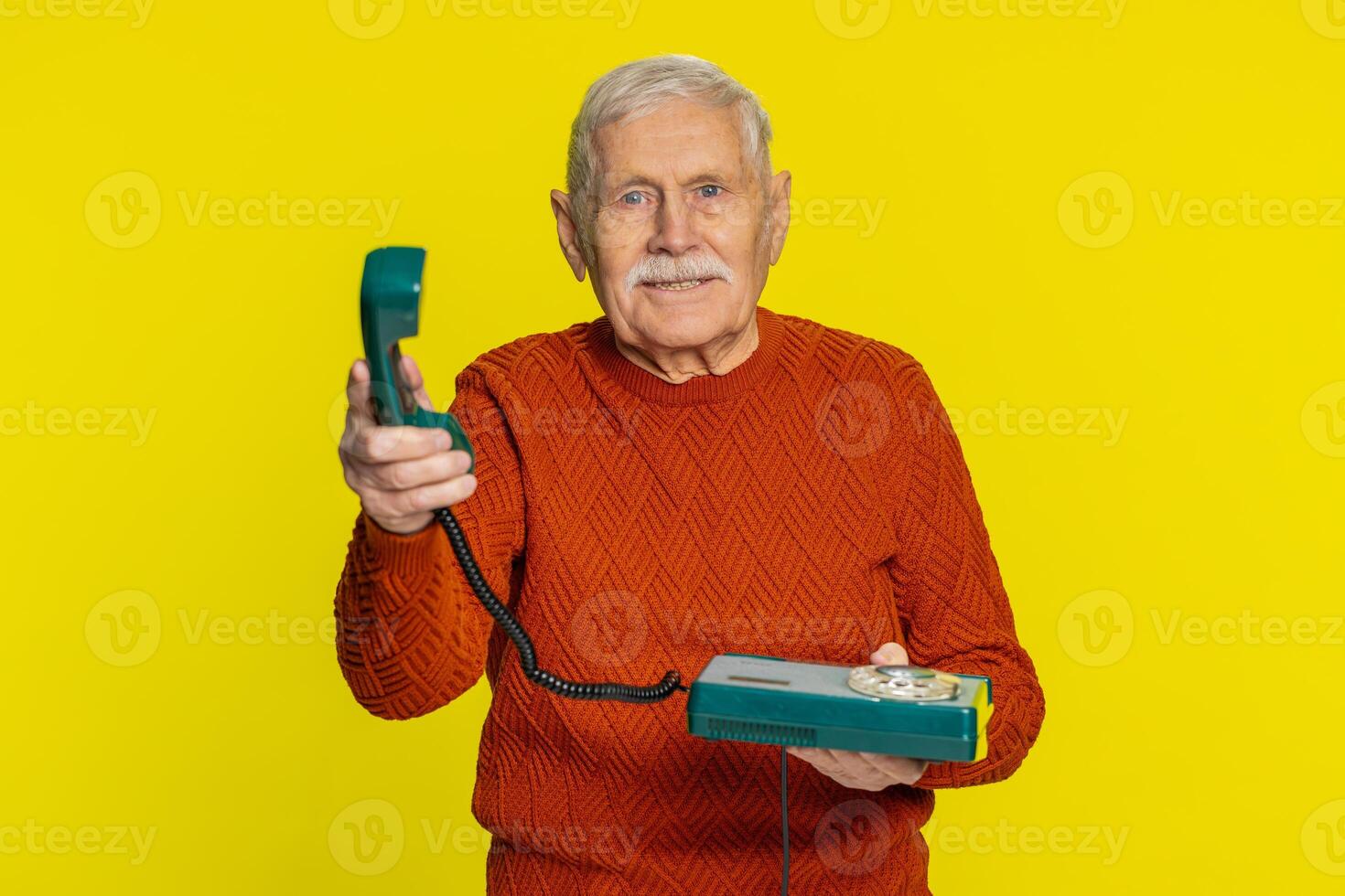 Senior man talking on wired landline vintage telephone, advertising proposition of conversation photo