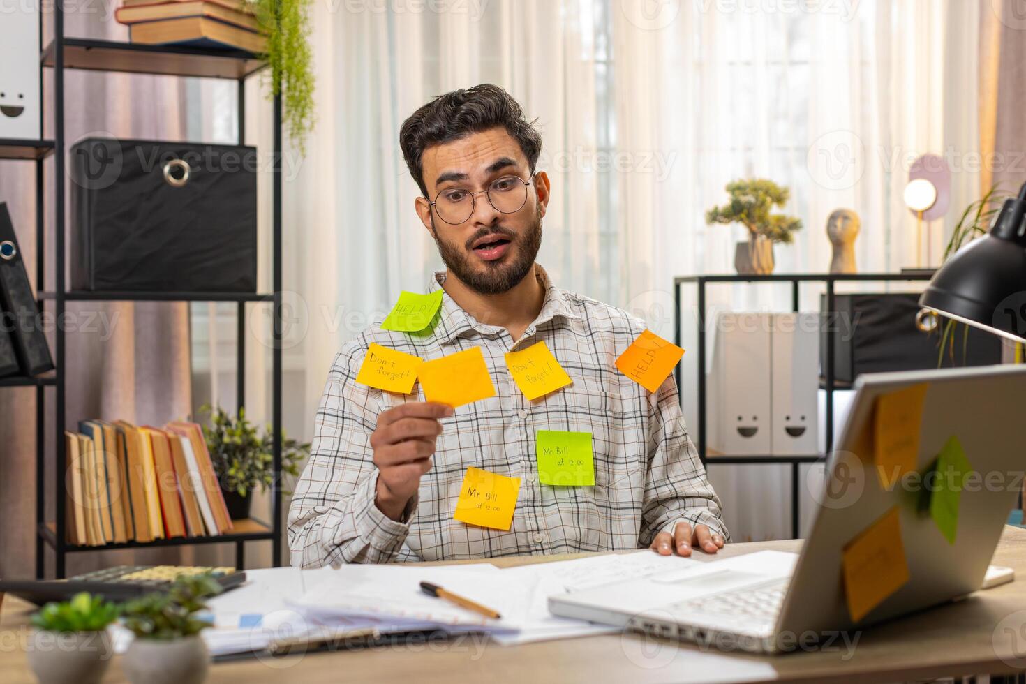 Indian businessman work on laptop sticky notes with many tasks inscription overworked at office photo