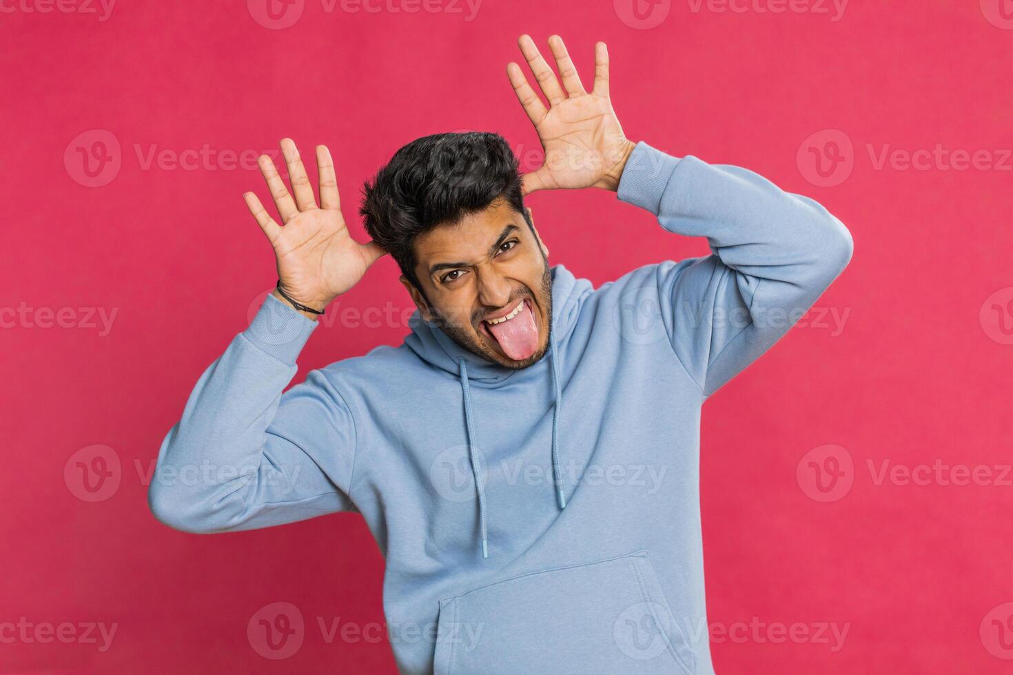 Funny comical Indian man making silly facial expressions, grimacing, fooling around, showing tongue photo