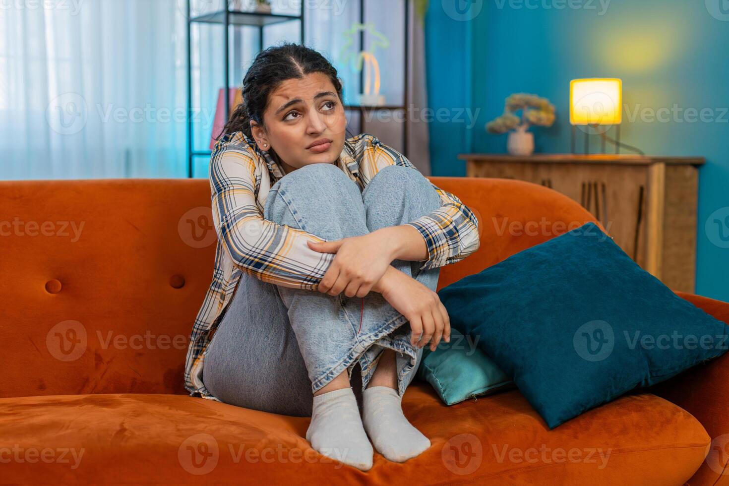 Indian woman on sofa holding head in hands frustrated exhausted I don't know gesture stressed photo