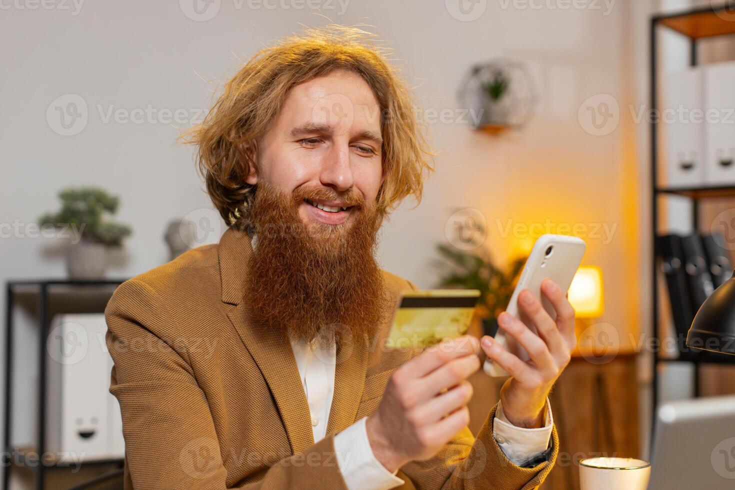 Business man using bank credit card and smartphone for online shopping payments at home office photo