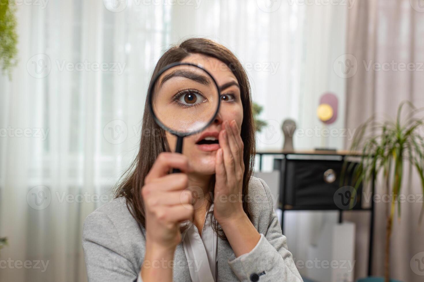 Investigator researcher businesswoman looking through magnifying glass with wow expression analyzing photo