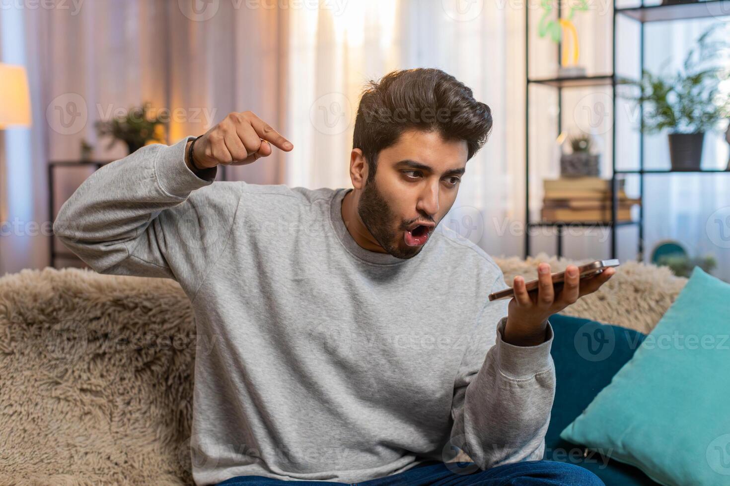Man talking on phone via speaker mode gesturing emotionally and looking irritated during an argument photo