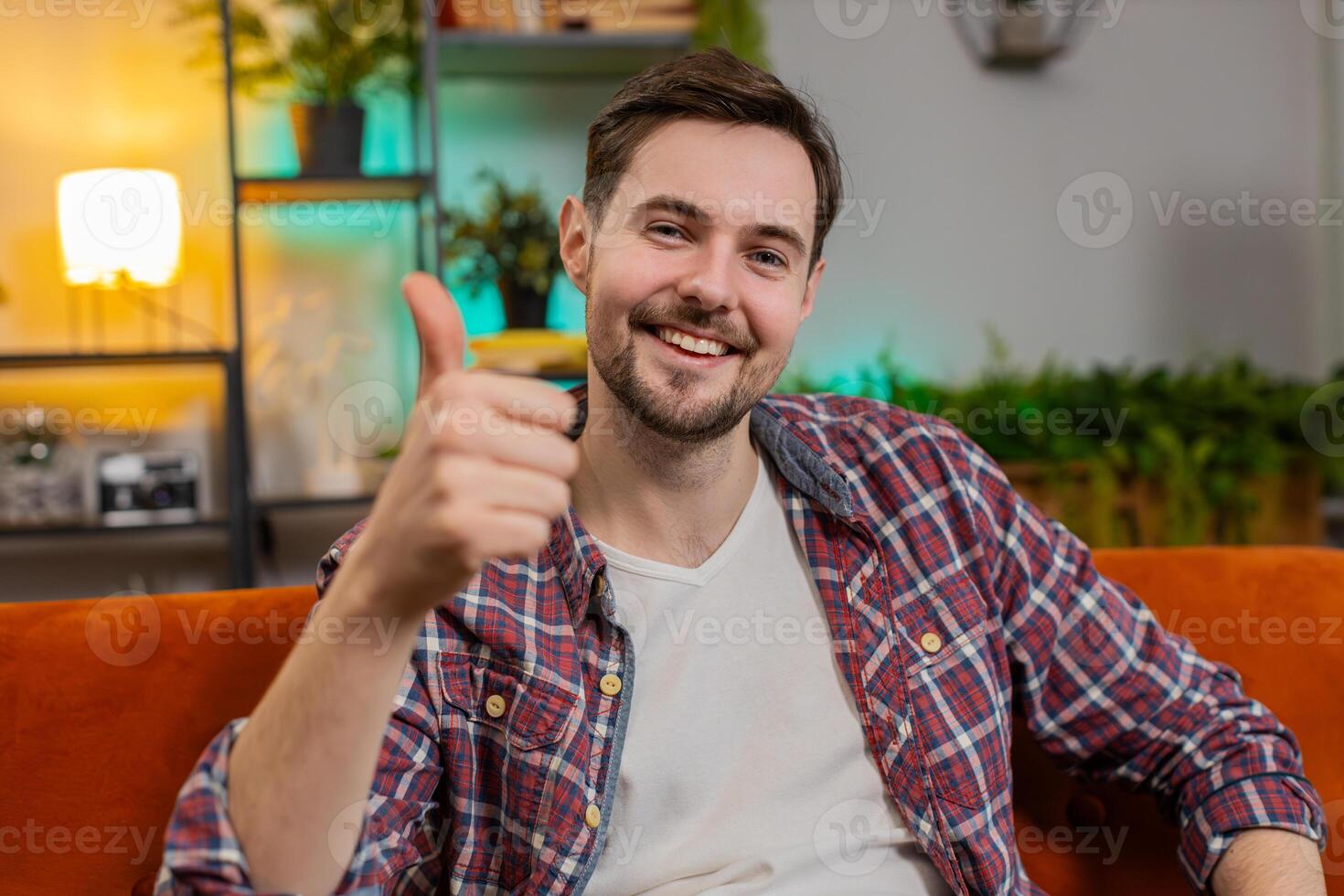 Happy man looking approvingly at camera showing double thumbs up like sign positive feedback at home photo