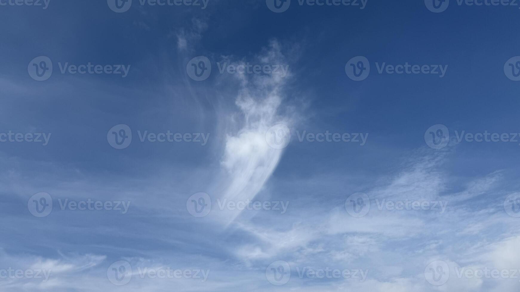 Wispy white clouds against a vibrant blue sky, symbolizing tranquility and serenity during a peaceful sunny summer day photo