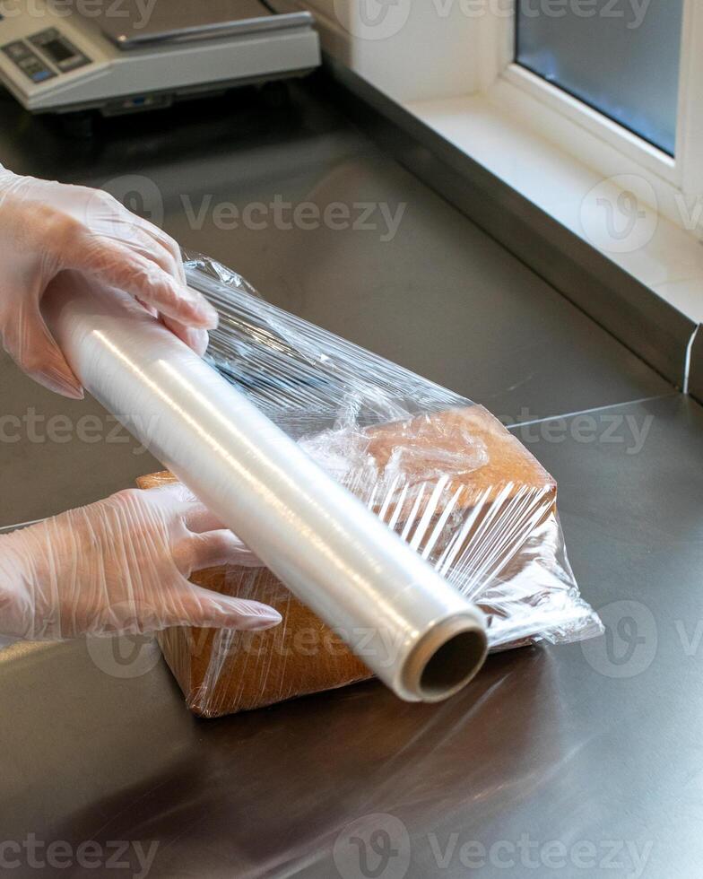 Protecting fresh loaf with plastic wrap on kitchen counter, food preservation, meal prep, hygienic storage, holiday cooking photo